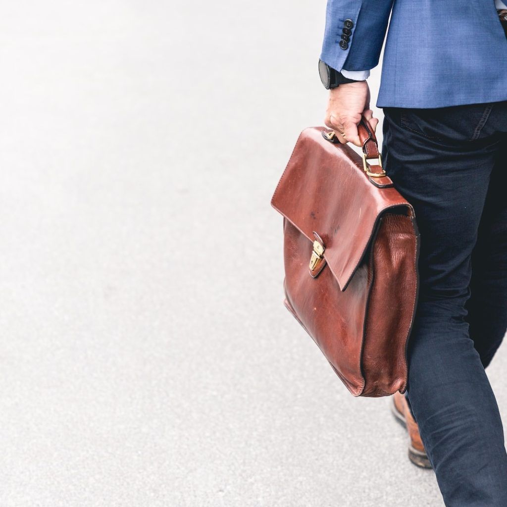 person walking holding brown leather bag