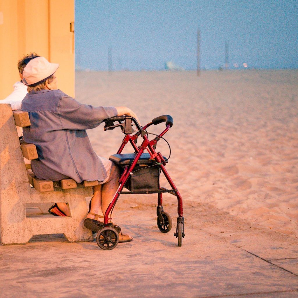 woman in gray dress shirt and white hat sitting on brown wooden bench near body of on on on on